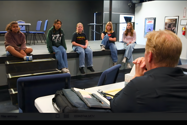 Students performing Frozen Jr. on stage with Arendelle castle backdrop and sparkling snow effects